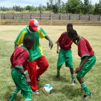 Coach Issac Gamba practices with three Amani soccer players.